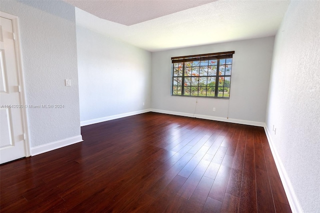 empty room featuring a textured ceiling and dark wood-type flooring