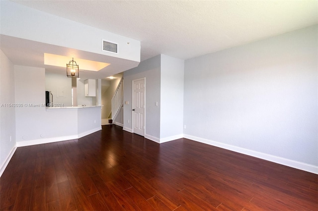 unfurnished living room with dark hardwood / wood-style flooring and a textured ceiling