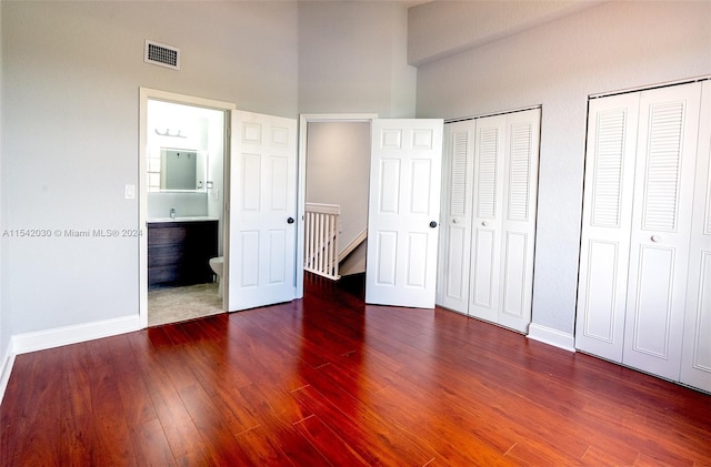 unfurnished bedroom with wood-type flooring and two closets