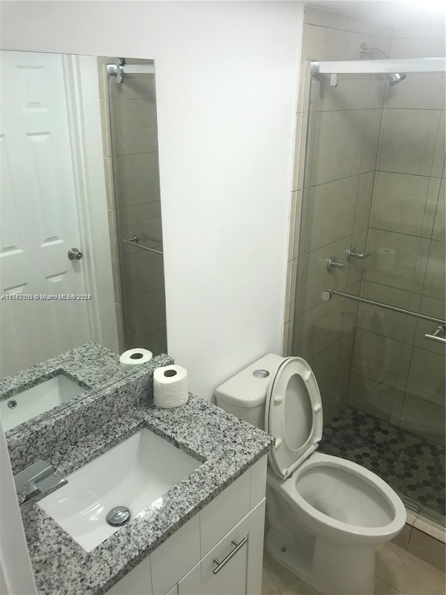 bathroom with walk in shower, tile flooring, vanity with extensive cabinet space, and toilet