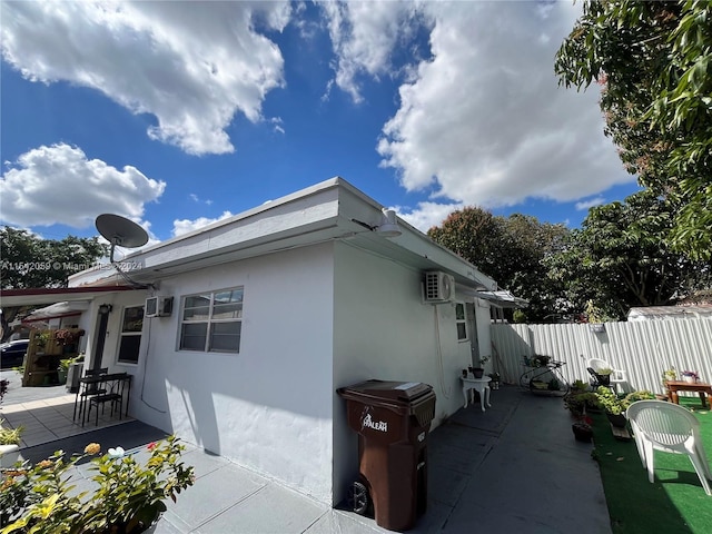 view of side of property with a patio area and a wall unit AC