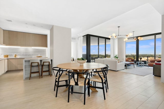 dining space featuring expansive windows, light hardwood / wood-style floors, and an inviting chandelier