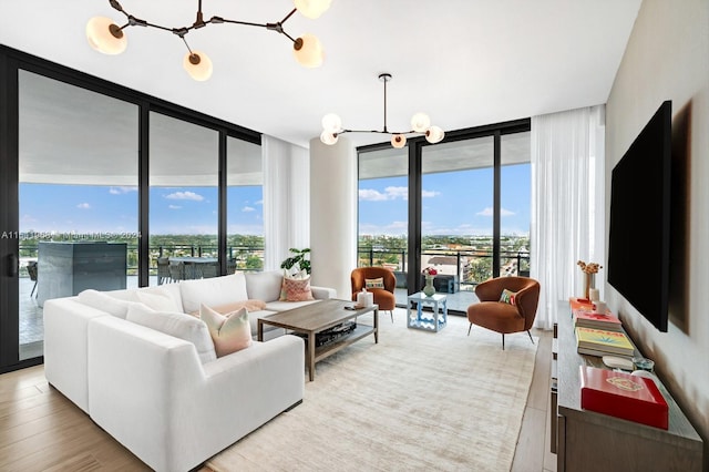 living room featuring plenty of natural light, floor to ceiling windows, a chandelier, and light hardwood / wood-style flooring