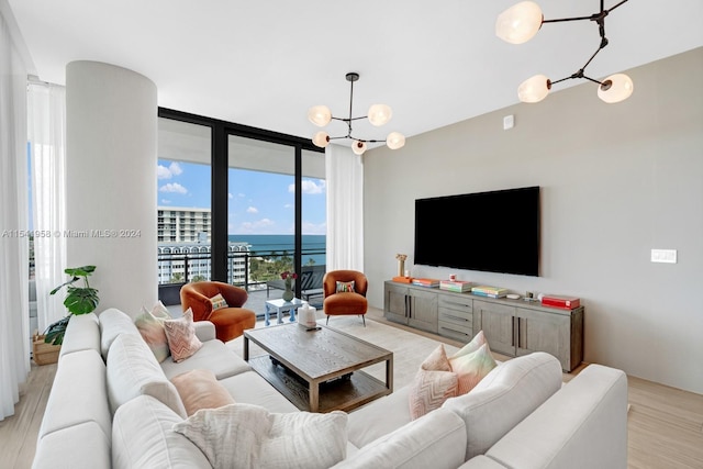 living room with floor to ceiling windows, a water view, a notable chandelier, and light hardwood / wood-style flooring