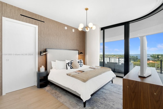 bedroom with expansive windows, access to exterior, a notable chandelier, and light wood-type flooring