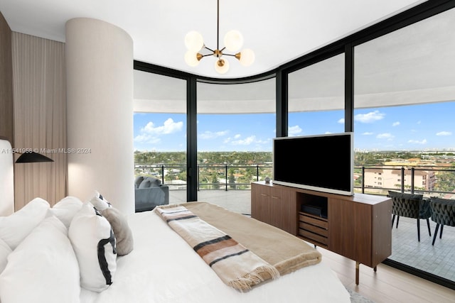 bedroom with a wall of windows, light wood-type flooring, and an inviting chandelier