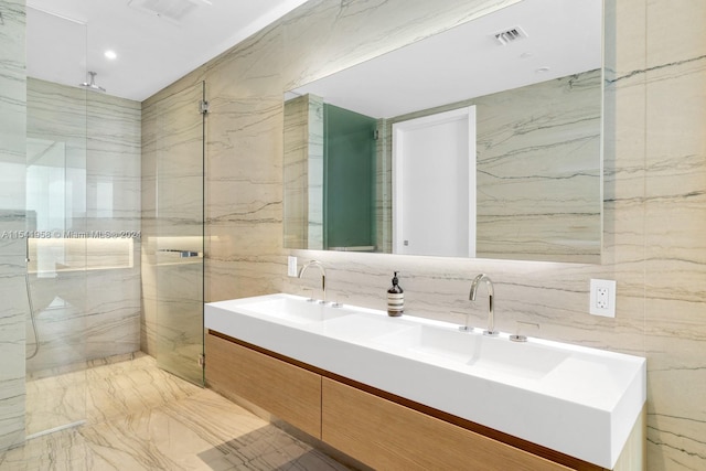 bathroom with tile walls, dual bowl vanity, and tiled shower