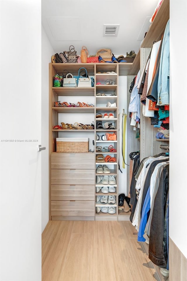 walk in closet with light hardwood / wood-style flooring