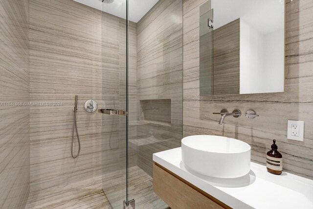 bathroom featuring an enclosed shower, vanity with extensive cabinet space, and tile walls