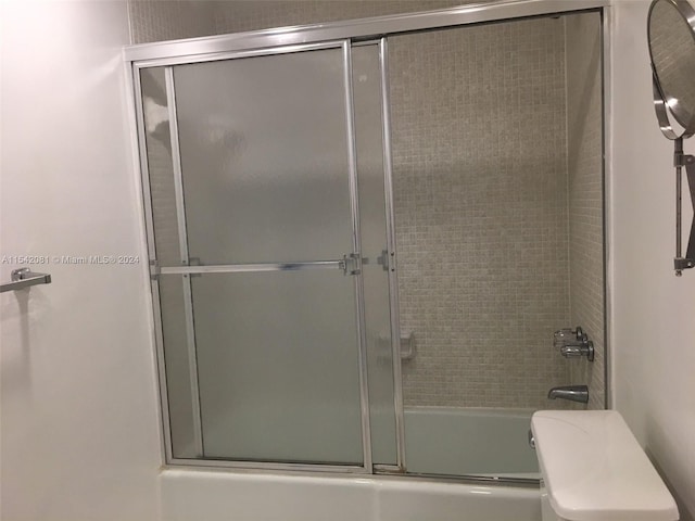 bathroom featuring combined bath / shower with glass door and toilet