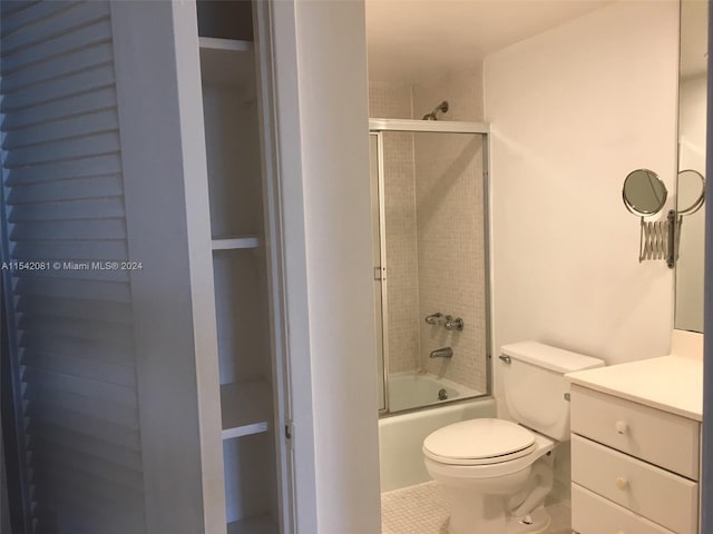 full bathroom featuring toilet, tile floors, large vanity, and enclosed tub / shower combo