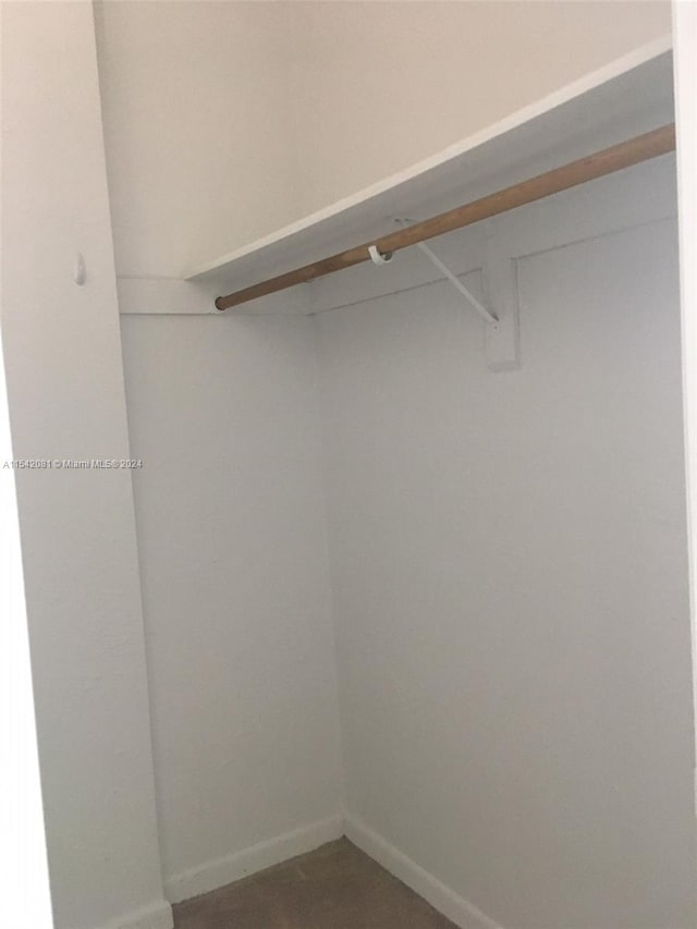 walk in closet with dark carpet