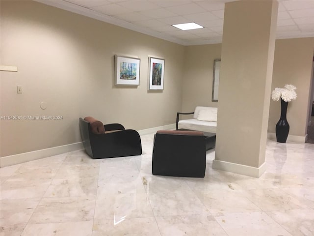 living area with a paneled ceiling and light tile floors