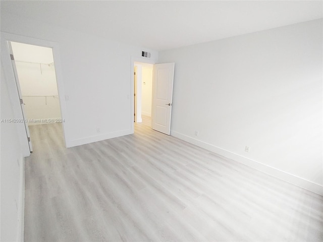 unfurnished bedroom with a walk in closet, a closet, and light hardwood / wood-style flooring