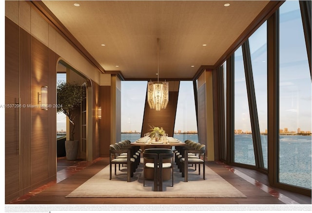 dining space featuring a wall of windows, a chandelier, dark wood-type flooring, and a water view