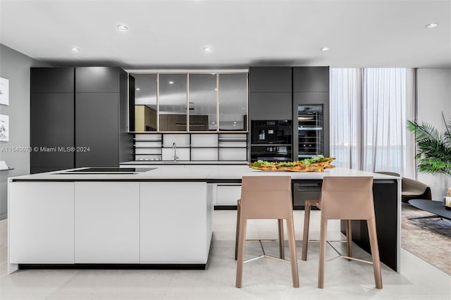 kitchen featuring gray cabinetry, a kitchen island, a breakfast bar area, and light tile floors