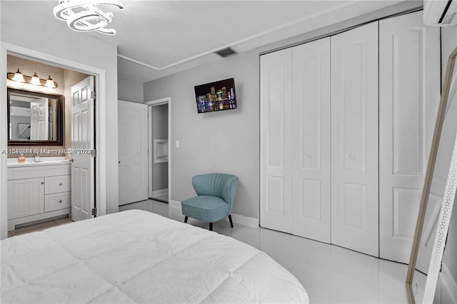 tiled bedroom with a wall unit AC, connected bathroom, sink, a chandelier, and a closet