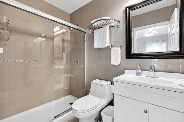 bathroom featuring tile walls, walk in shower, toilet, and vanity