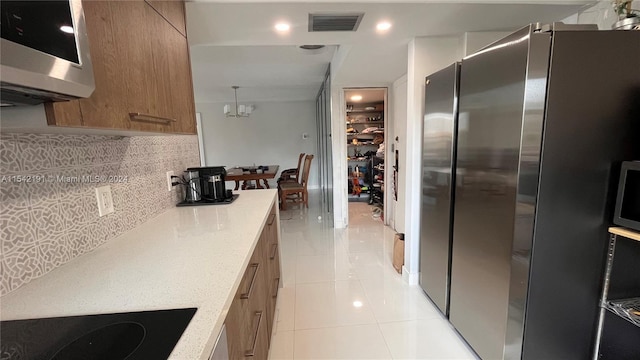 kitchen with backsplash, hanging light fixtures, appliances with stainless steel finishes, light tile patterned flooring, and a chandelier