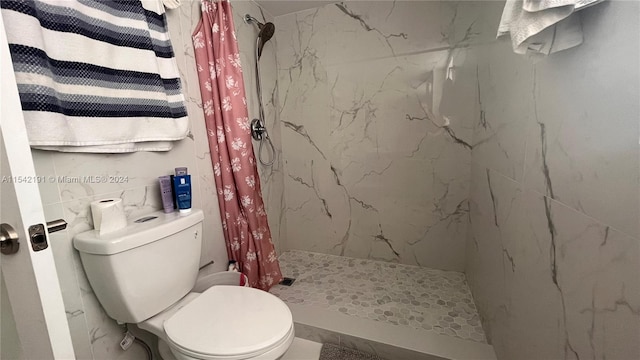 bathroom featuring a shower with shower curtain, toilet, and tile walls