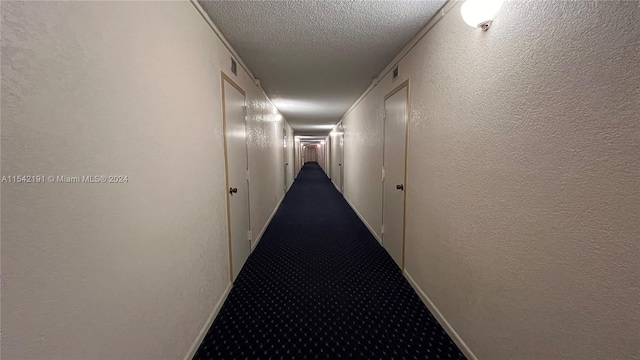 hall with carpet floors and a textured ceiling