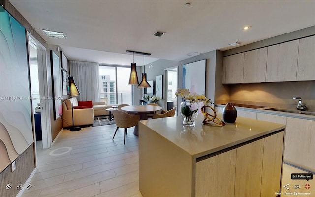 kitchen with a center island, decorative light fixtures, light brown cabinets, and sink