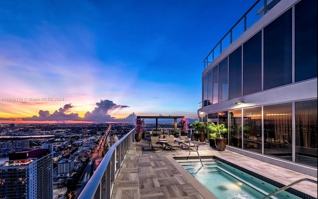 pool at dusk featuring a hot tub