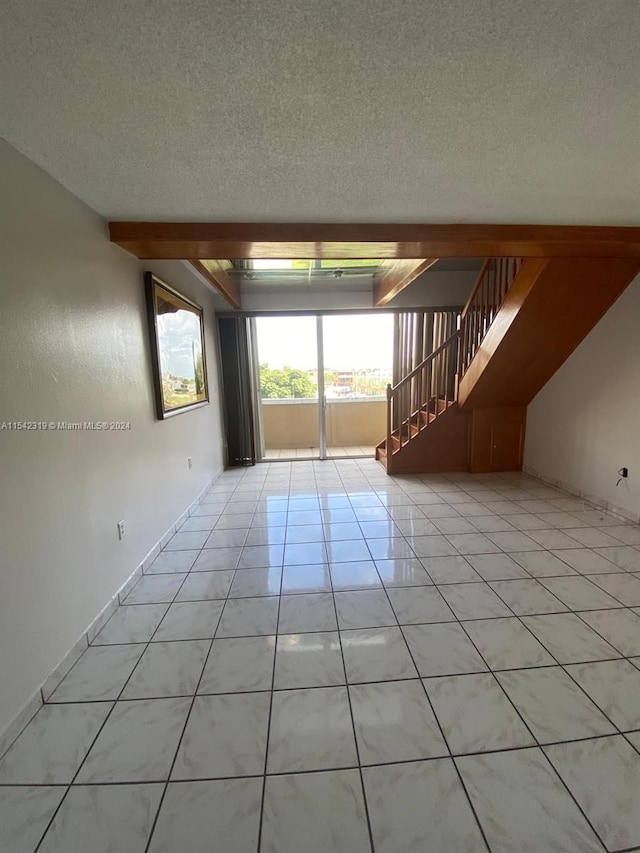 spare room featuring light tile floors and a textured ceiling