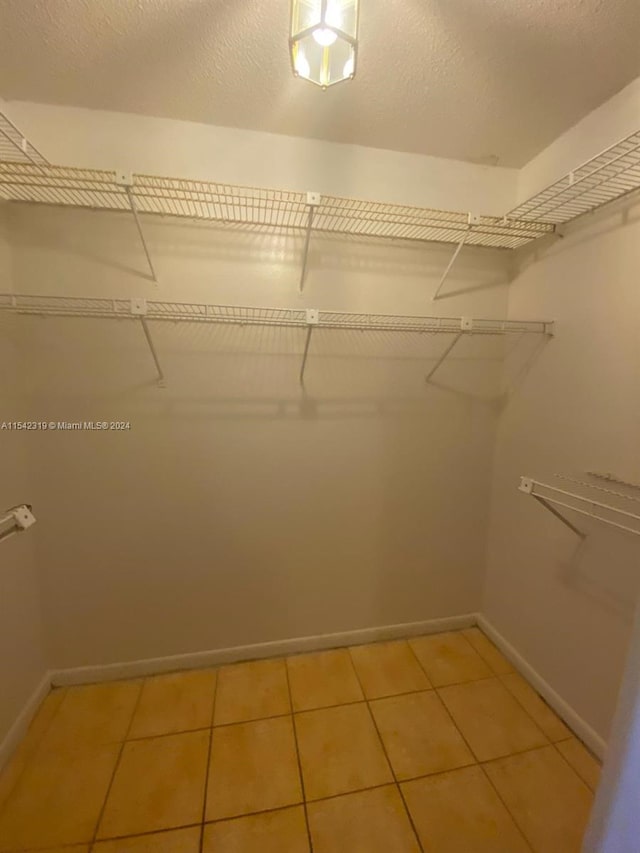 walk in closet with light tile floors