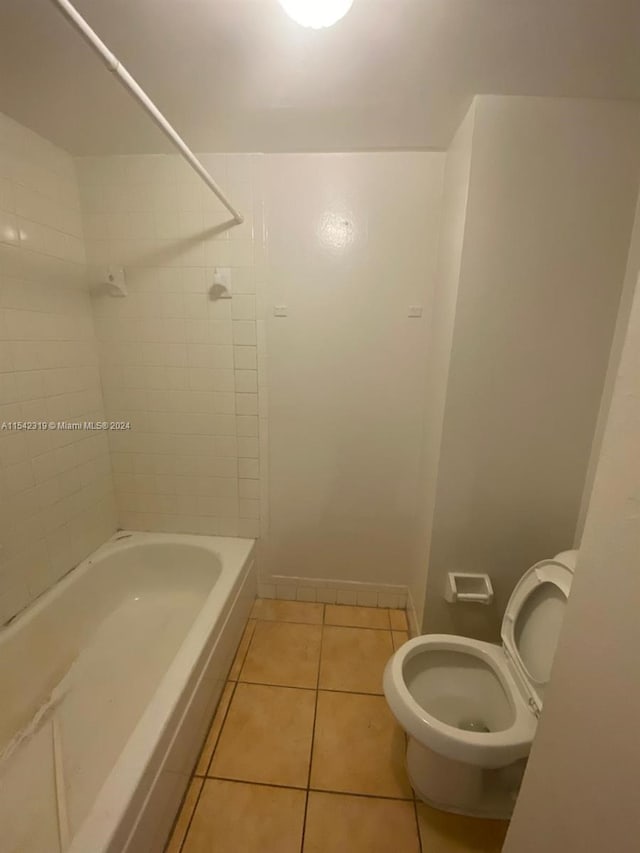 bathroom with tiled shower / bath combo, toilet, and tile flooring