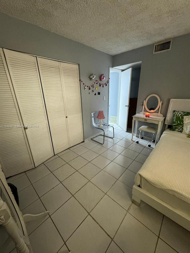 unfurnished bedroom with a textured ceiling, a closet, and light tile floors