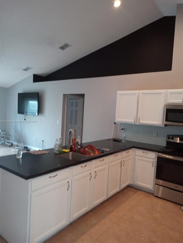 kitchen featuring appliances with stainless steel finishes, sink, white cabinetry, vaulted ceiling, and light tile patterned floors