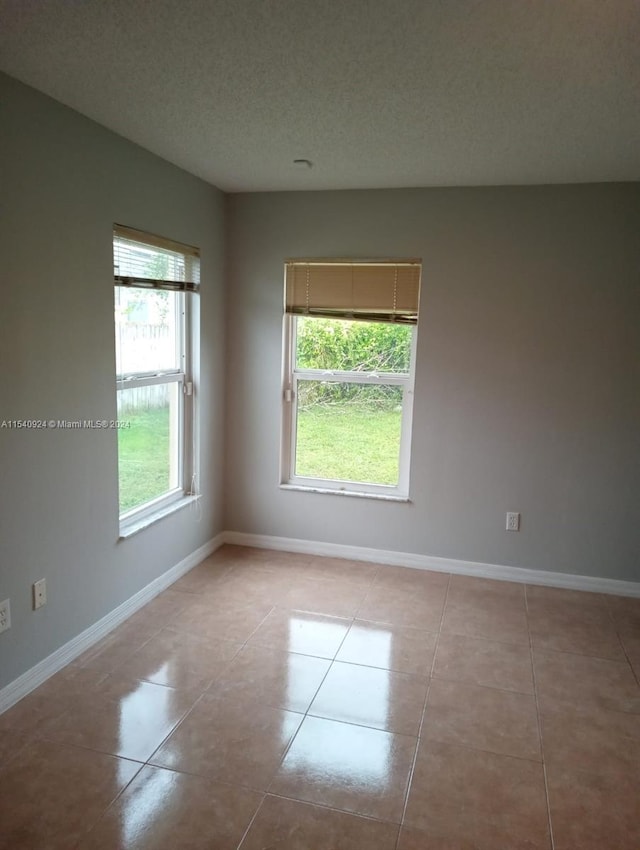 tiled empty room featuring a textured ceiling