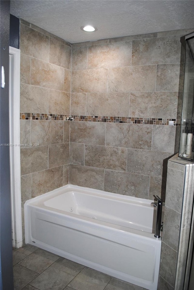 bathroom featuring a bath, a textured ceiling, and tile patterned flooring