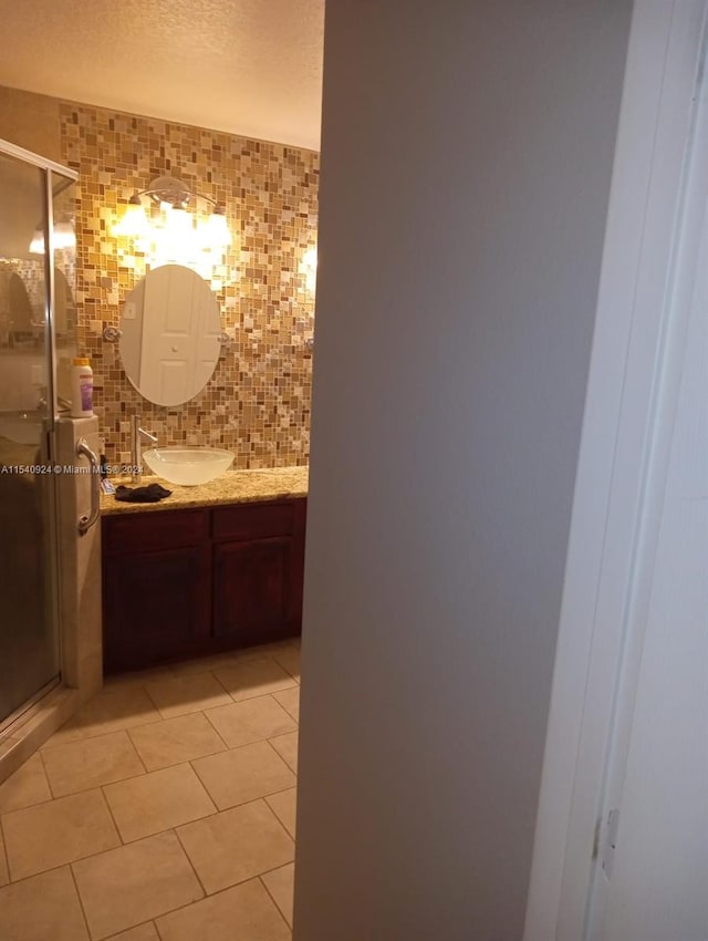 bathroom featuring vanity, decorative backsplash, tile patterned flooring, and a shower with door