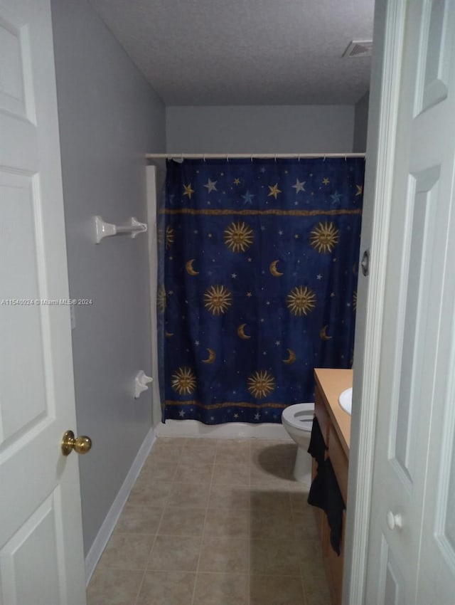 bathroom with vanity, toilet, a textured ceiling, and tile patterned flooring