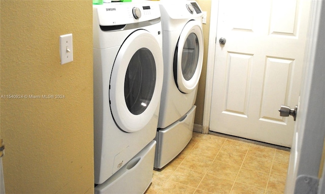 clothes washing area with light tile patterned flooring and washing machine and clothes dryer