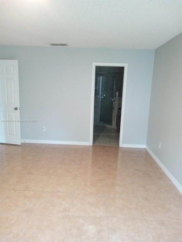 empty room featuring a textured ceiling and light tile patterned floors