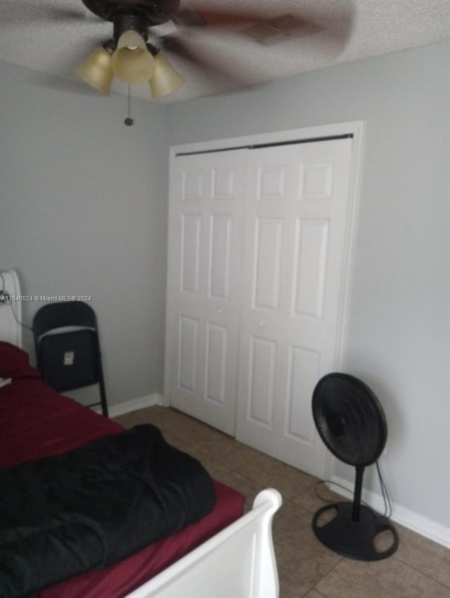 tiled bedroom with a textured ceiling, a closet, and ceiling fan