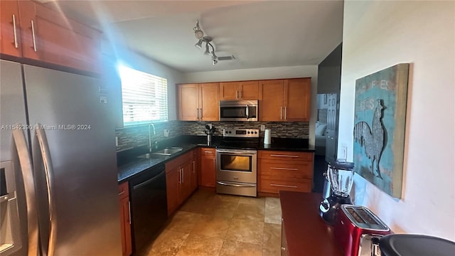 kitchen featuring sink, rail lighting, appliances with stainless steel finishes, backsplash, and light tile flooring