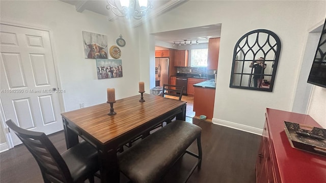 dining area featuring dark hardwood / wood-style flooring, rail lighting, and an inviting chandelier