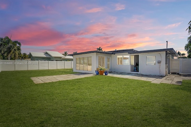 back house at dusk featuring a yard