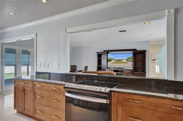 kitchen featuring stainless steel range with electric stovetop, light tile patterned floors, crown molding, and dark stone counters