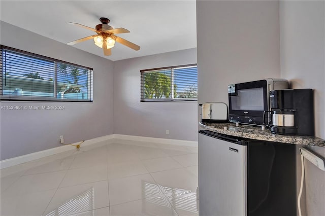 kitchen featuring ceiling fan, light tile patterned flooring, and stainless steel refrigerator