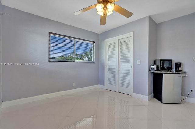 tiled bedroom featuring refrigerator, a closet, and ceiling fan