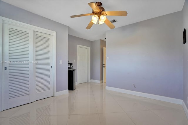 unfurnished bedroom featuring ceiling fan, light tile patterned floors, and a closet