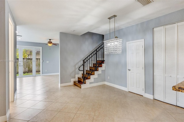 tiled foyer with ceiling fan with notable chandelier