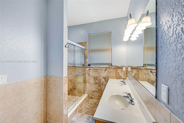 bathroom featuring walk in shower, dual vanity, and tile walls