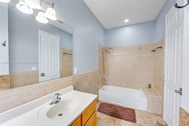 bathroom with vanity, tile flooring, tile walls, and tiled shower / bath