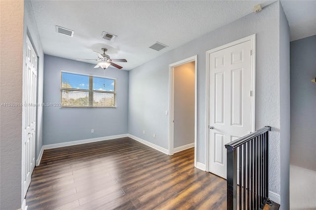 unfurnished room featuring a textured ceiling, dark hardwood / wood-style floors, and ceiling fan